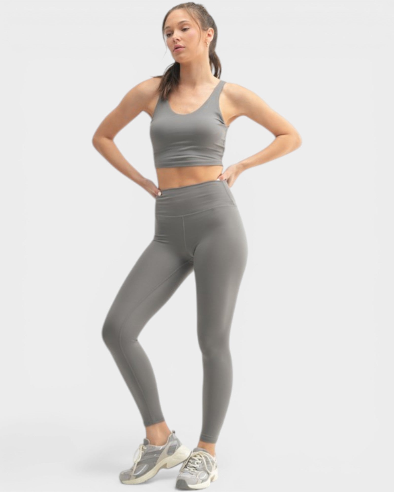 Woman wearing a gray athletic outfit on a white background