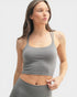 Woman wearing a gray tank top and leggings on a light gray background