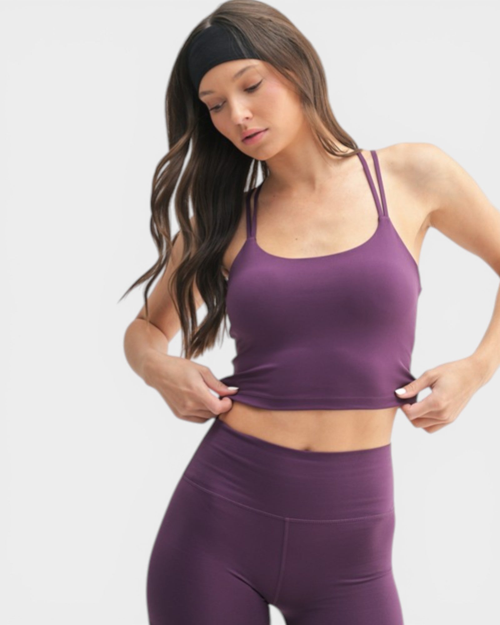Woman wearing a purple sports bra and leggings on a white background