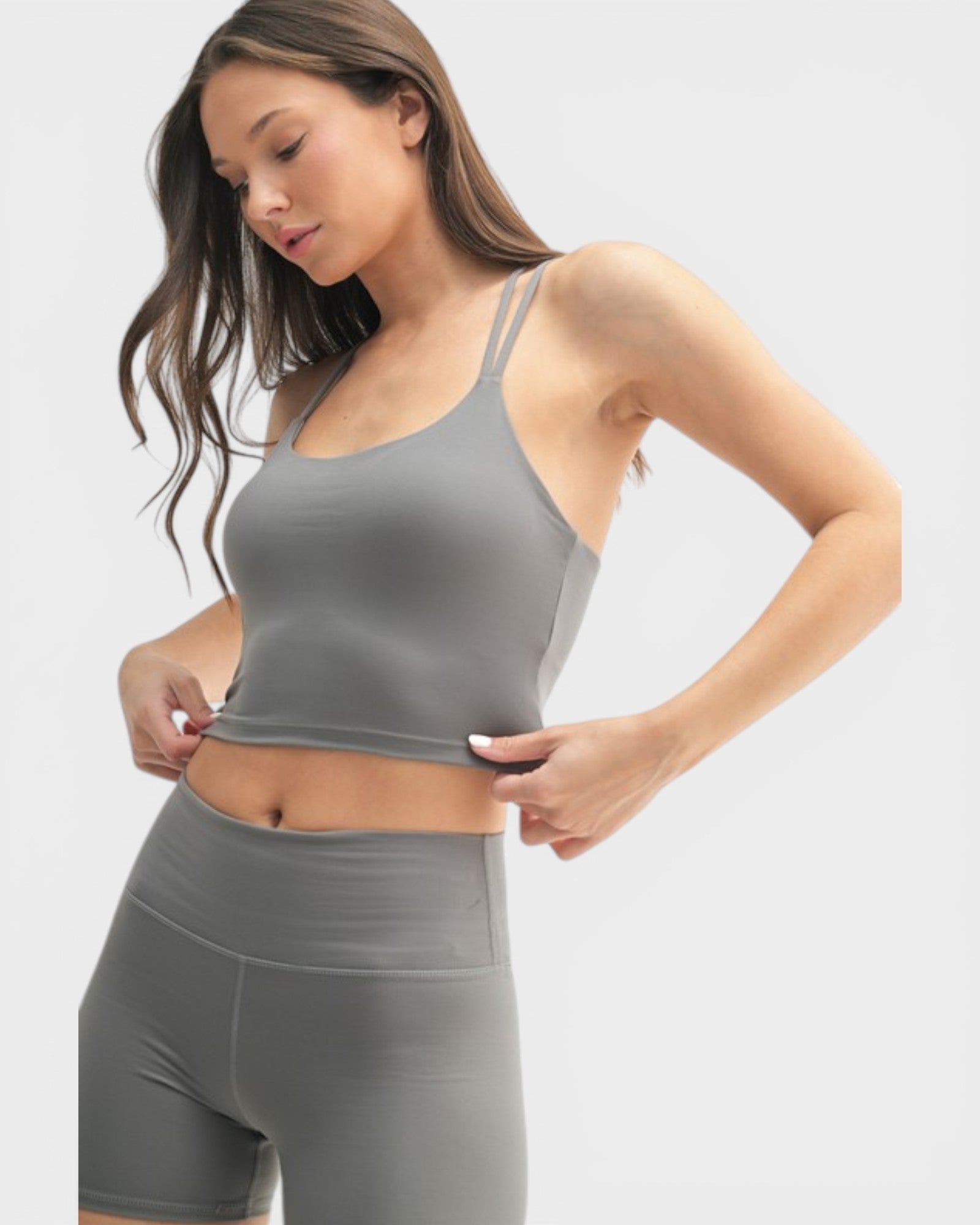 Woman wearing a gray athletic outfit on a light gray background