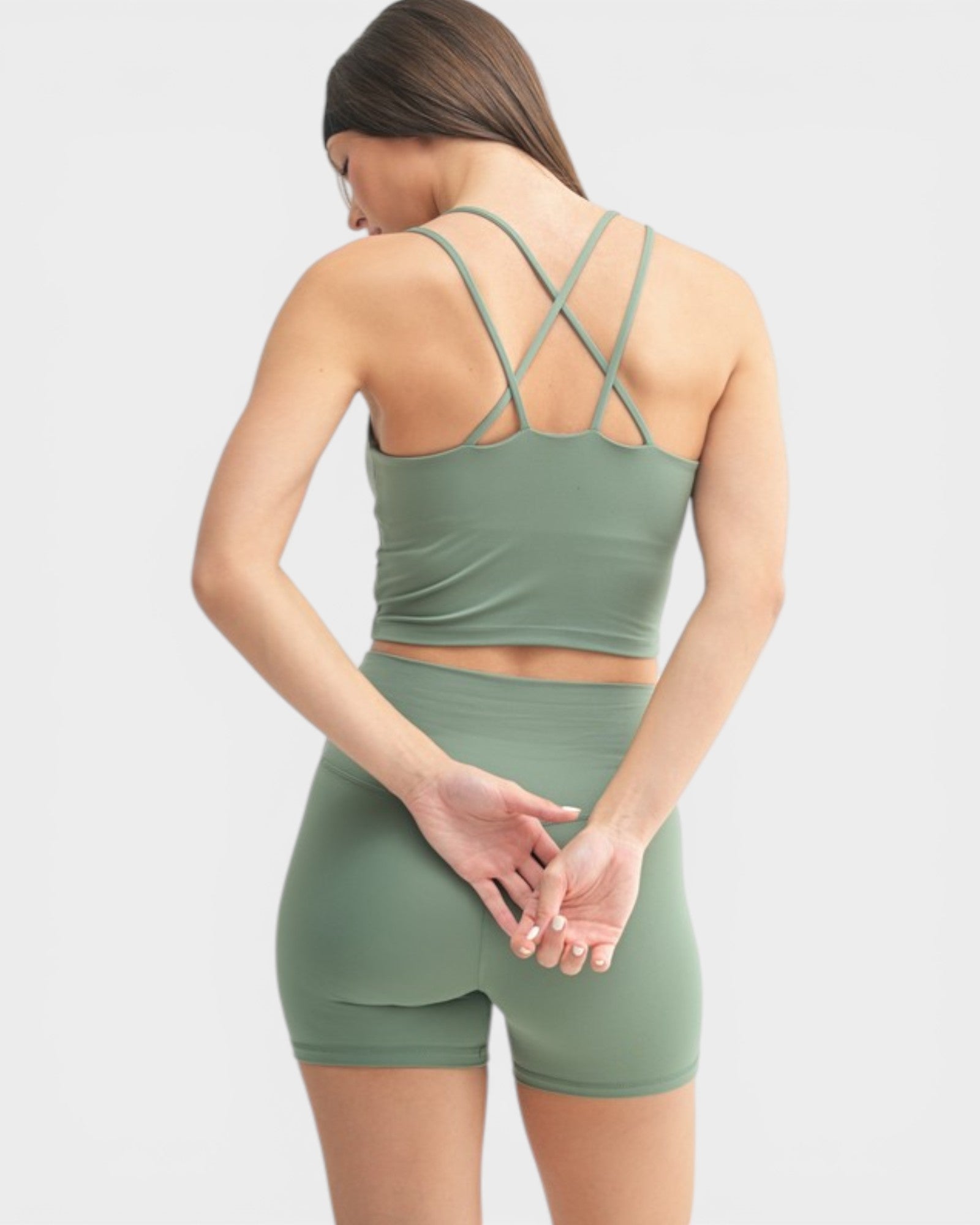 Woman wearing a green sports bra and shorts set on a white background