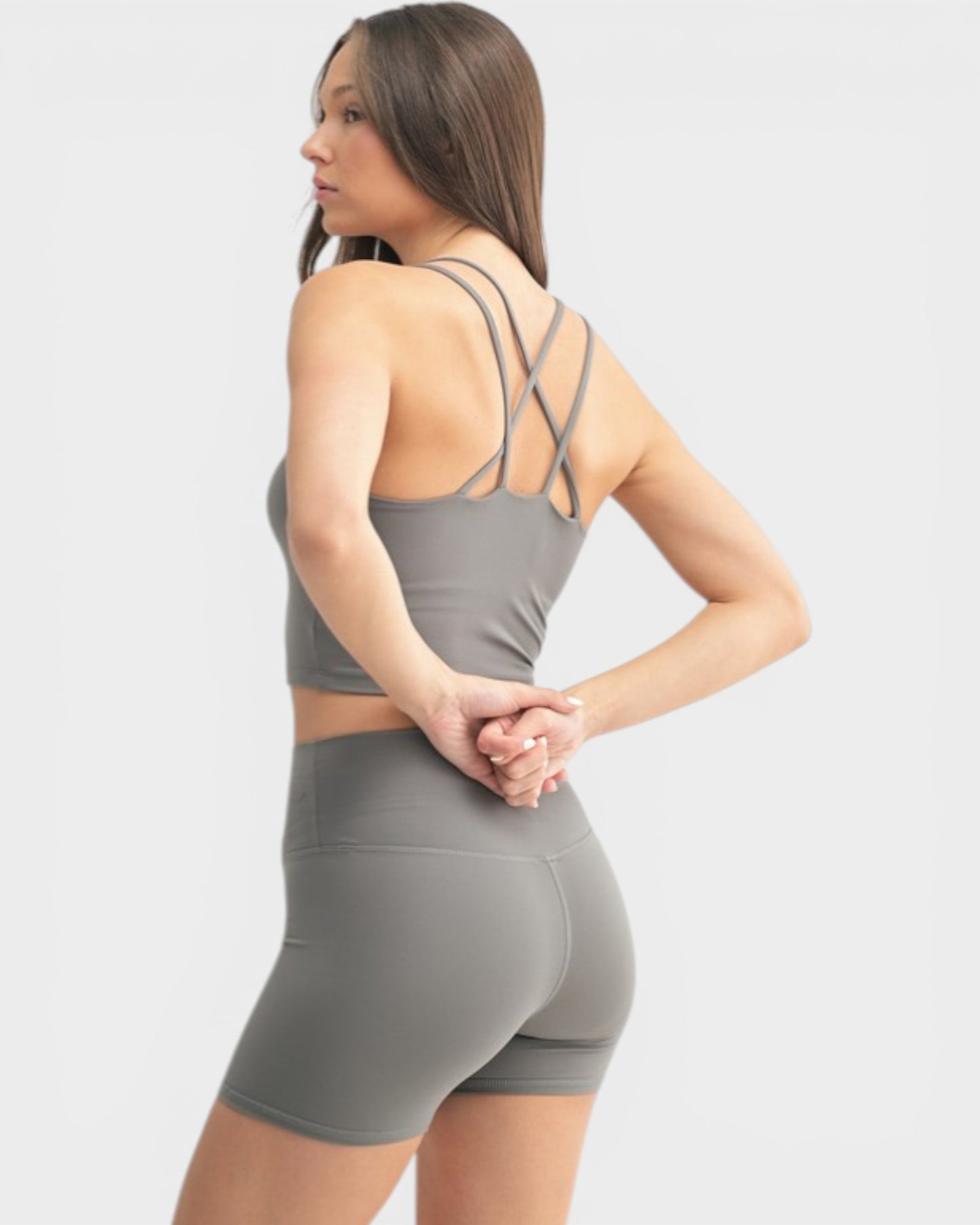 Woman wearing a gray sports bra and shorts set on a white background