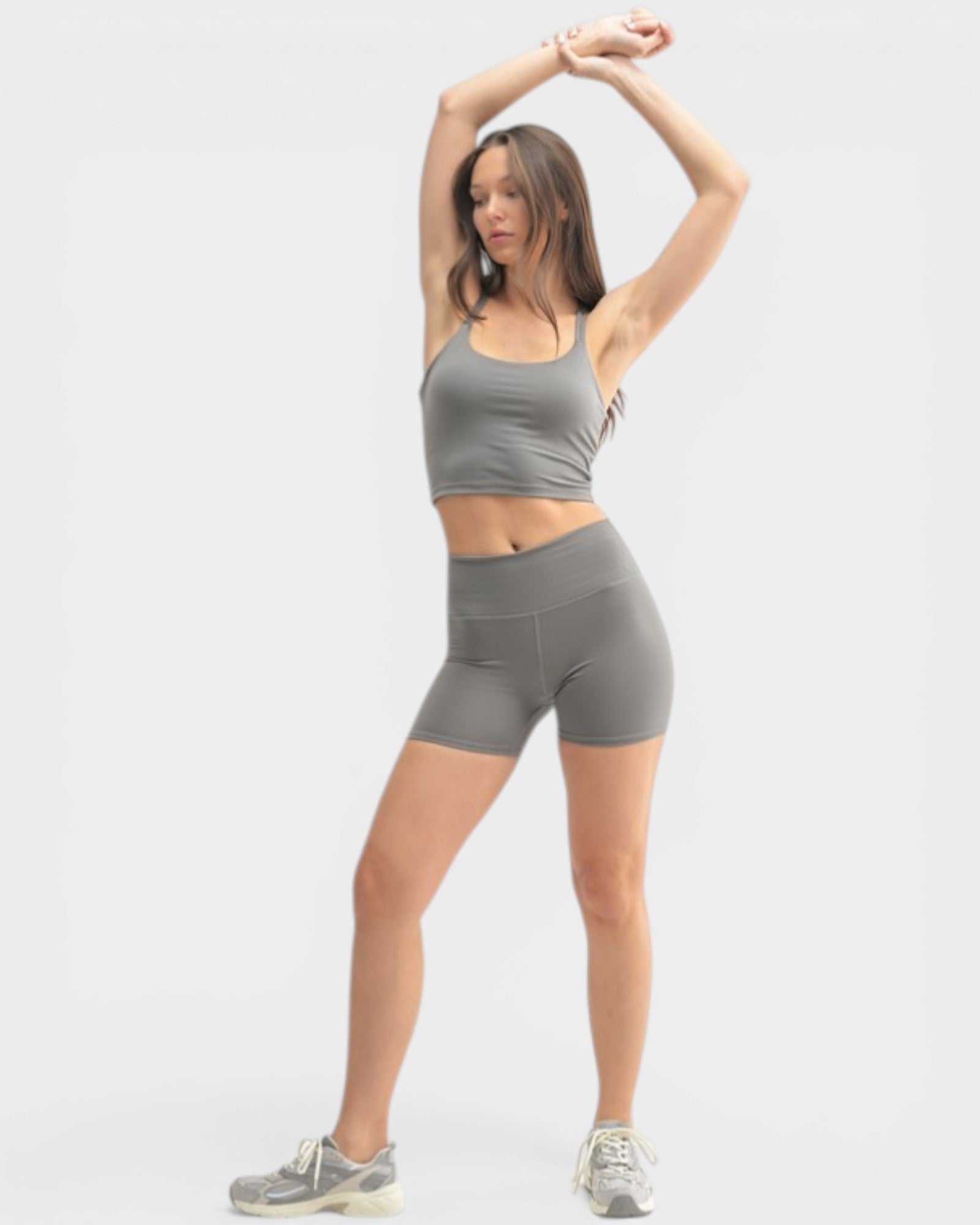 Woman in gray athletic wear posing against a white background