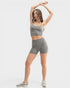 Woman in gray athletic wear posing against a white background