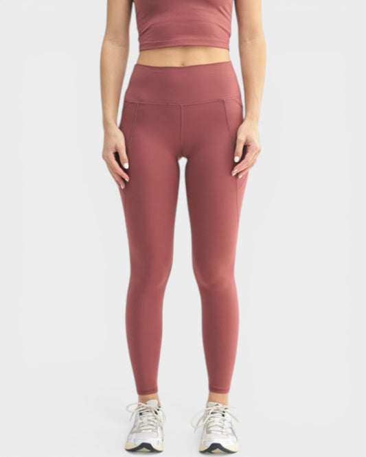 Person wearing maroon leggings and top on a white background