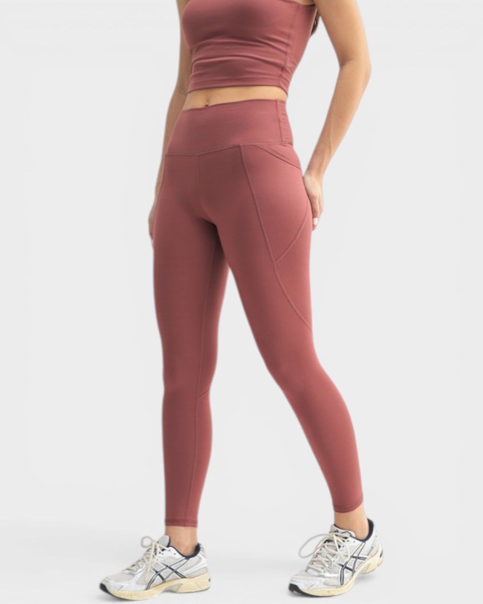 Person wearing maroon athletic leggings and crop top on a white background