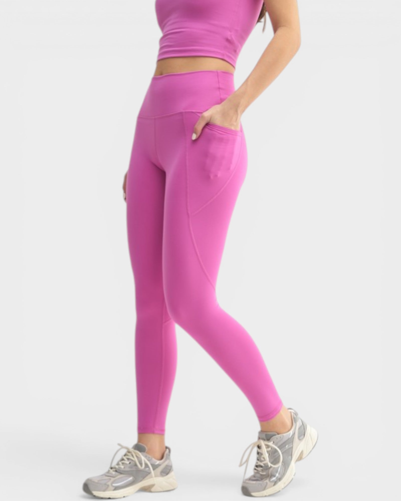 Person wearing bright pink leggings and a matching top on a white background