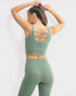 Person wearing a green sports bra and leggings set on a white background