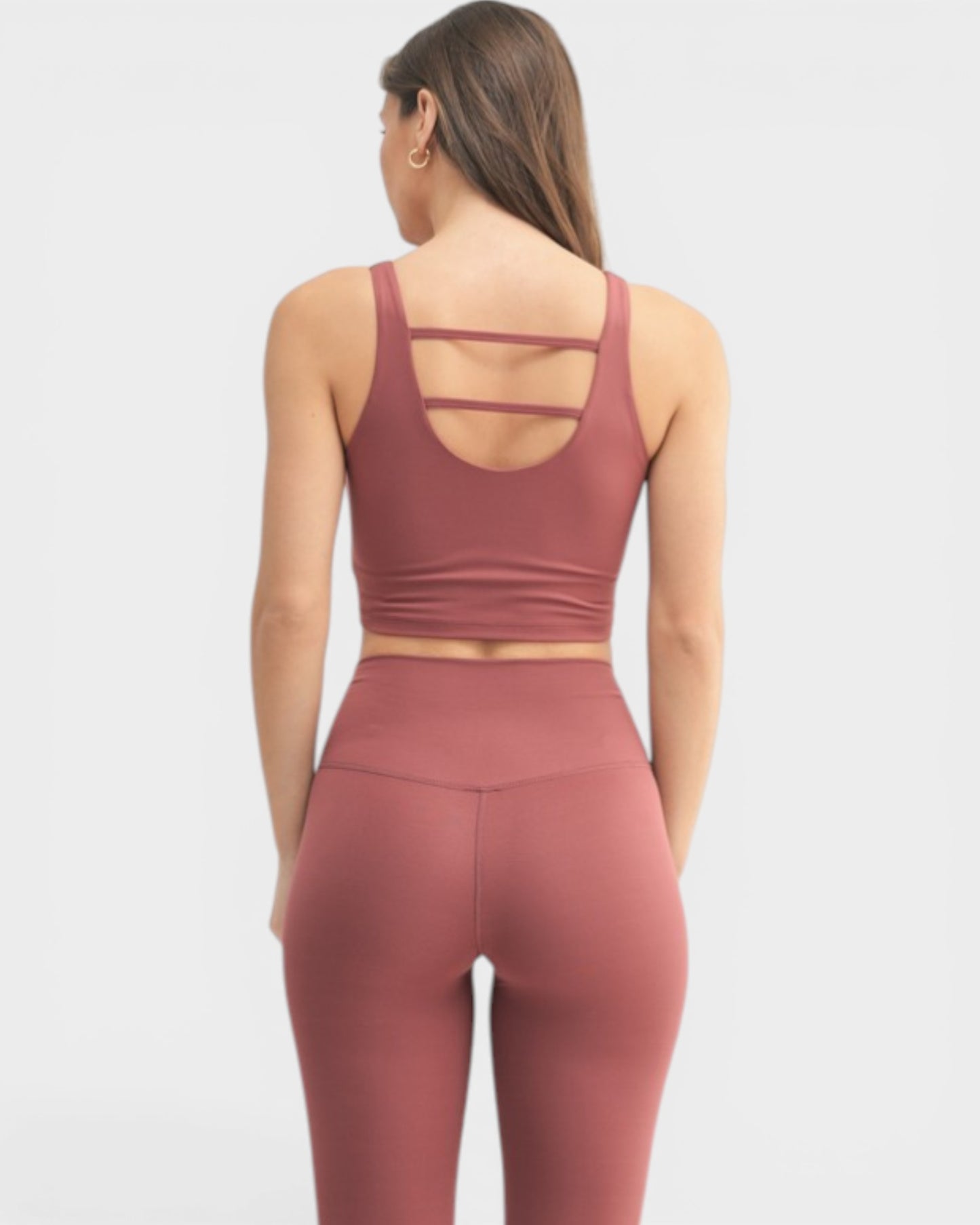 Person wearing a mauve sports bra and leggings set on a white background