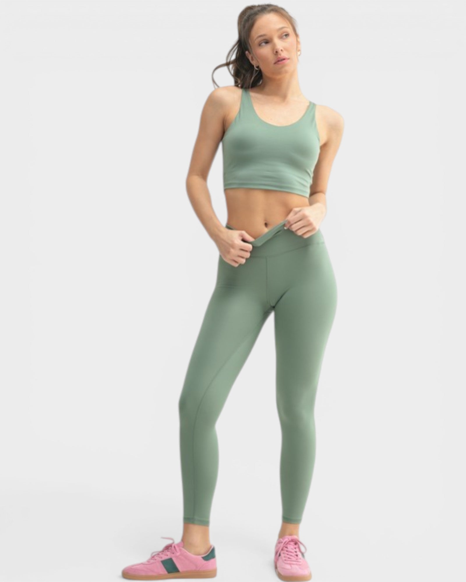 Woman wearing a green sports bra and leggings set on a white background
