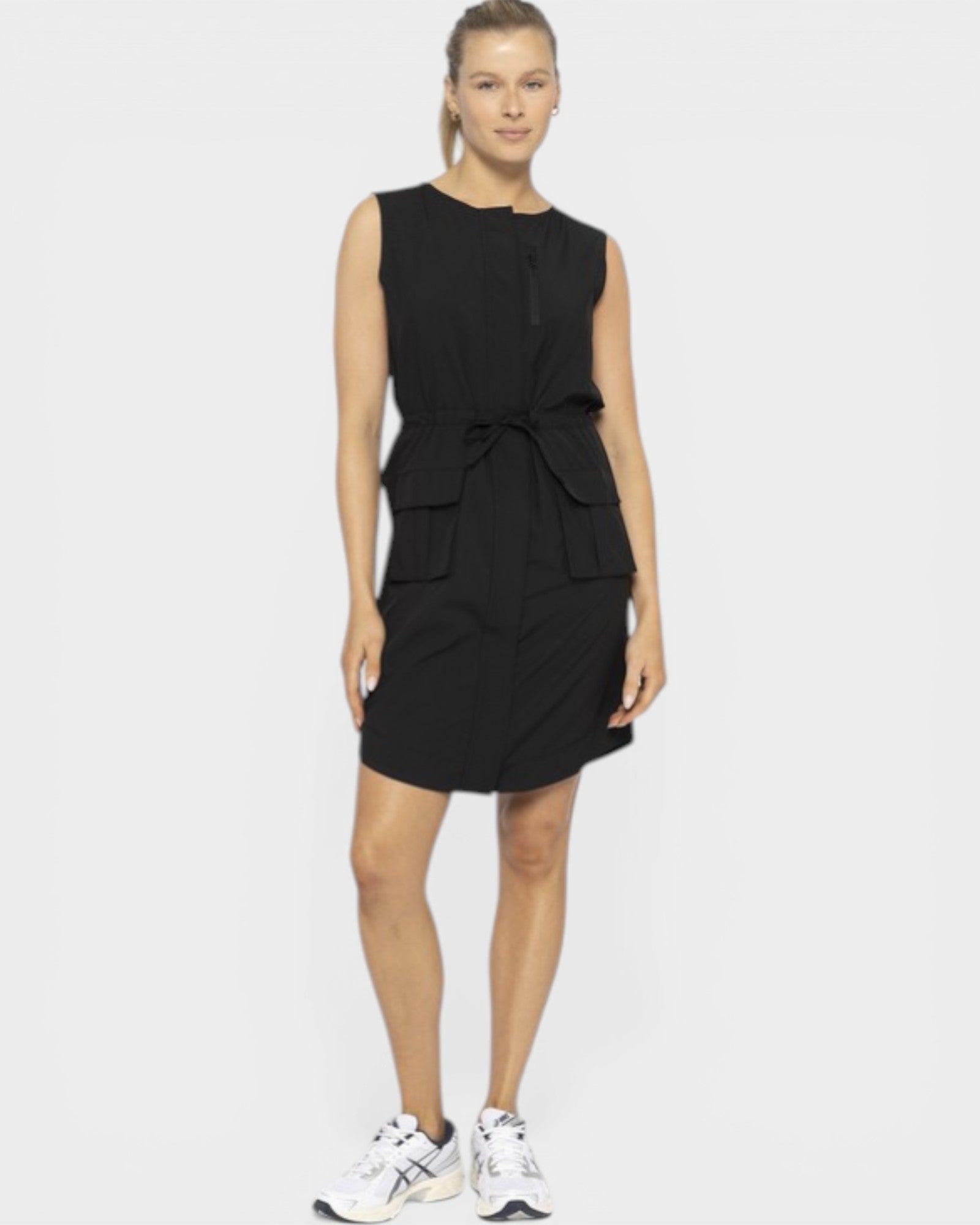 Woman wearing a black sleeveless dress with a tie detail on a white background