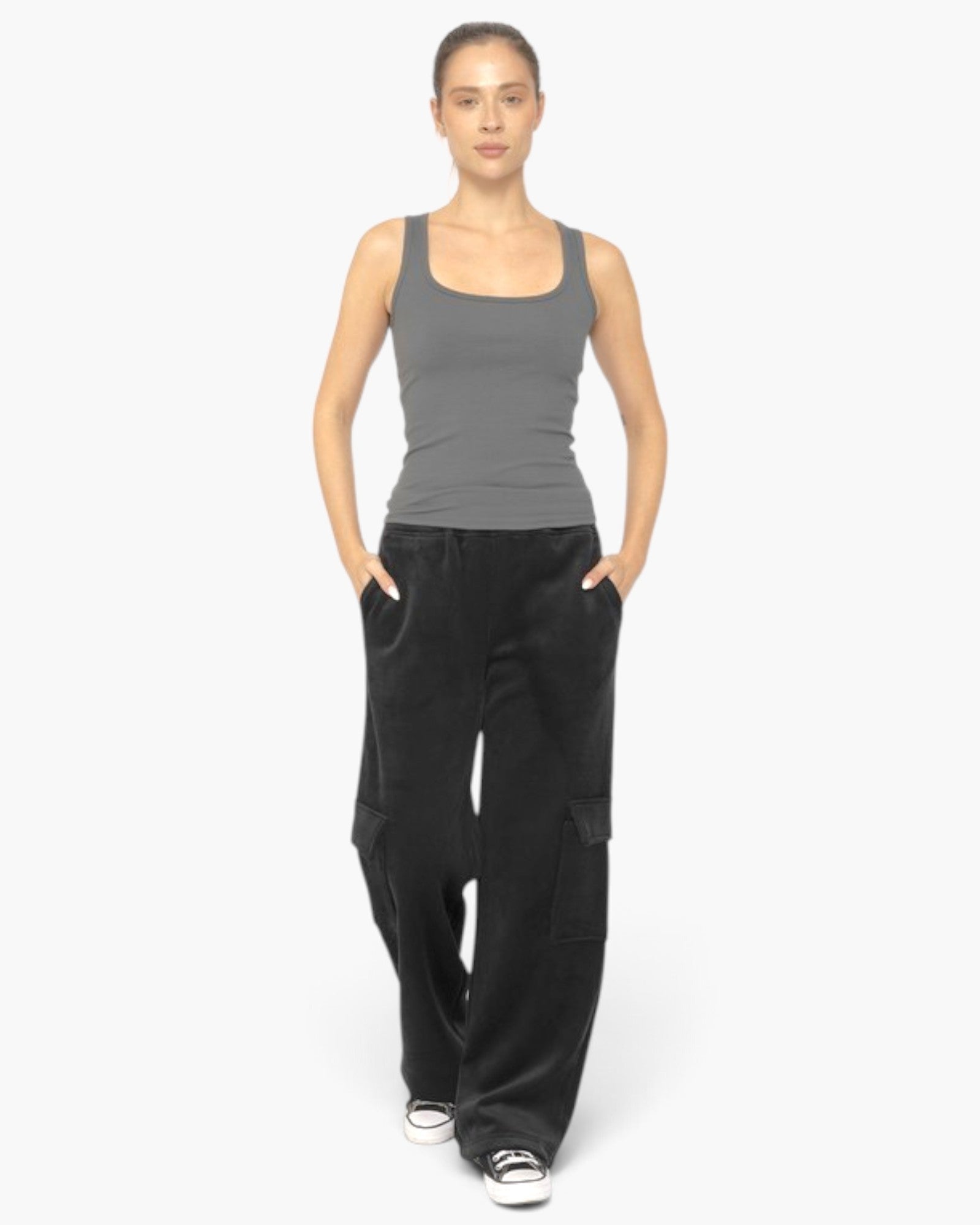 A woman modeling a gray sleeveless tank top and black wide-leg cargo pants against a plain light gray studio background.