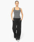 A woman modeling a gray sleeveless tank top and black wide-leg cargo pants against a plain light gray studio background.