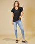 Woman wearing a black top and blue jeans on a beige background