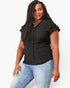 A woman modeling a black short-sleeve blouse with ruffled sleeves and vertical eyelet embroidery, paired with light blue jeans, against a plain white studio background.