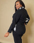 Woman wearing a black outfit with plaid accents on a beige background