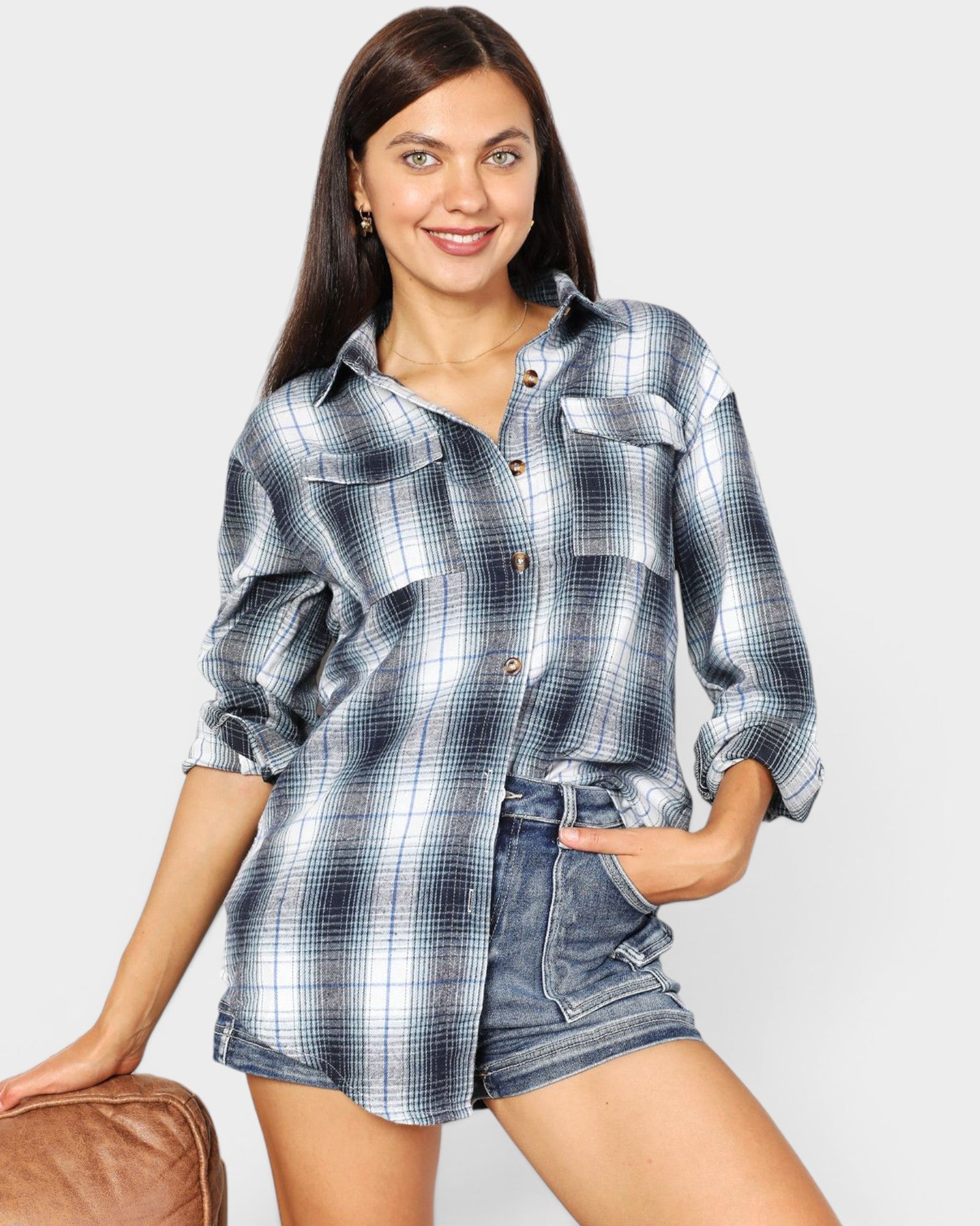 Woman wearing a plaid shirt and denim shorts on a plain background