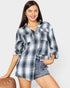 Woman wearing a plaid shirt and denim shorts on a plain background