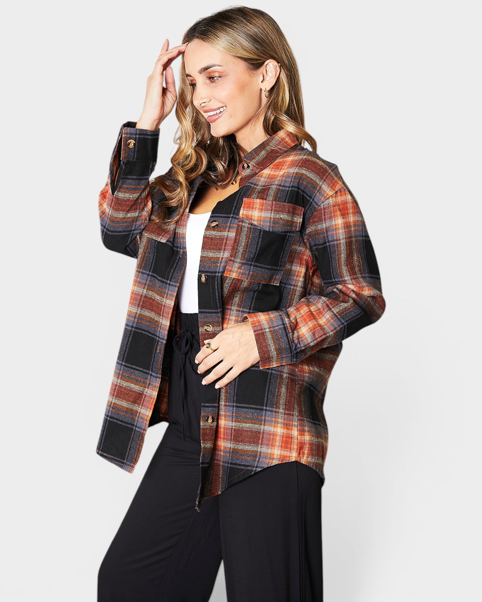 Woman wearing a plaid shirt over a white top on a light gray background