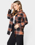 Woman wearing a plaid shirt over a white top on a light gray background