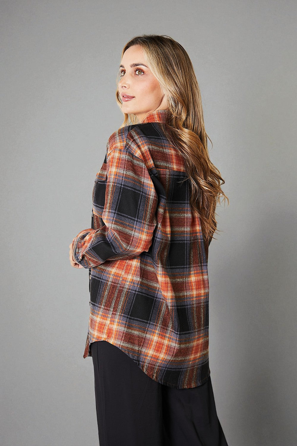 Woman wearing a plaid shirt against a gray background