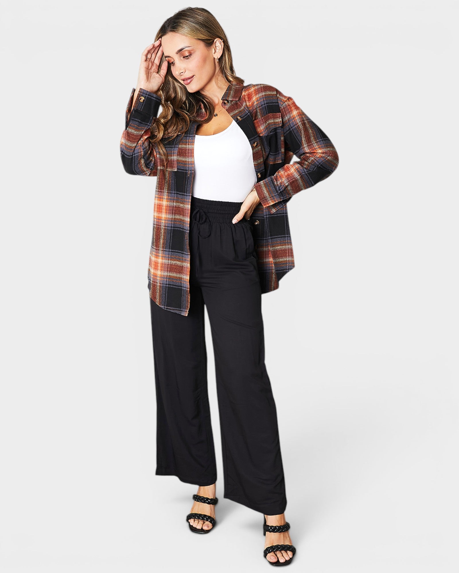 Woman wearing a plaid shirt and black pants on a white background