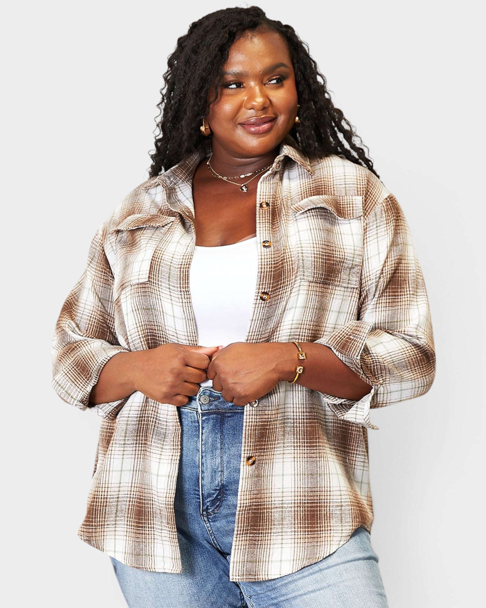 Woman wearing a plaid shirt over a white top and jeans on a light gray background