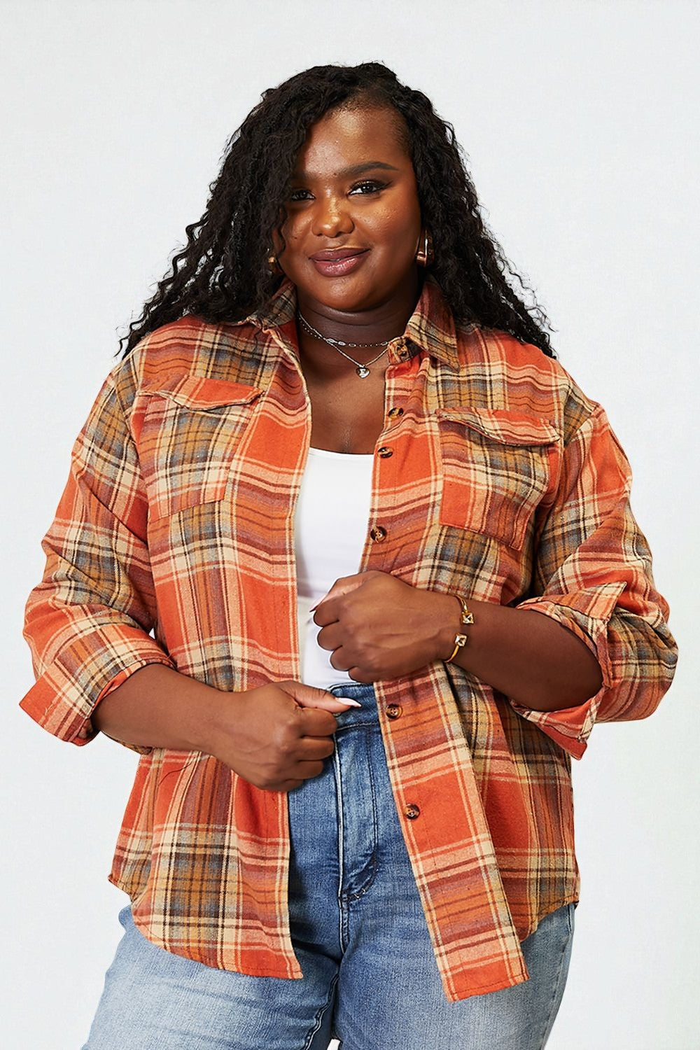 Woman wearing an orange plaid shirt and blue jeans against a white background