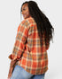 Person wearing an orange plaid shirt with a plain background