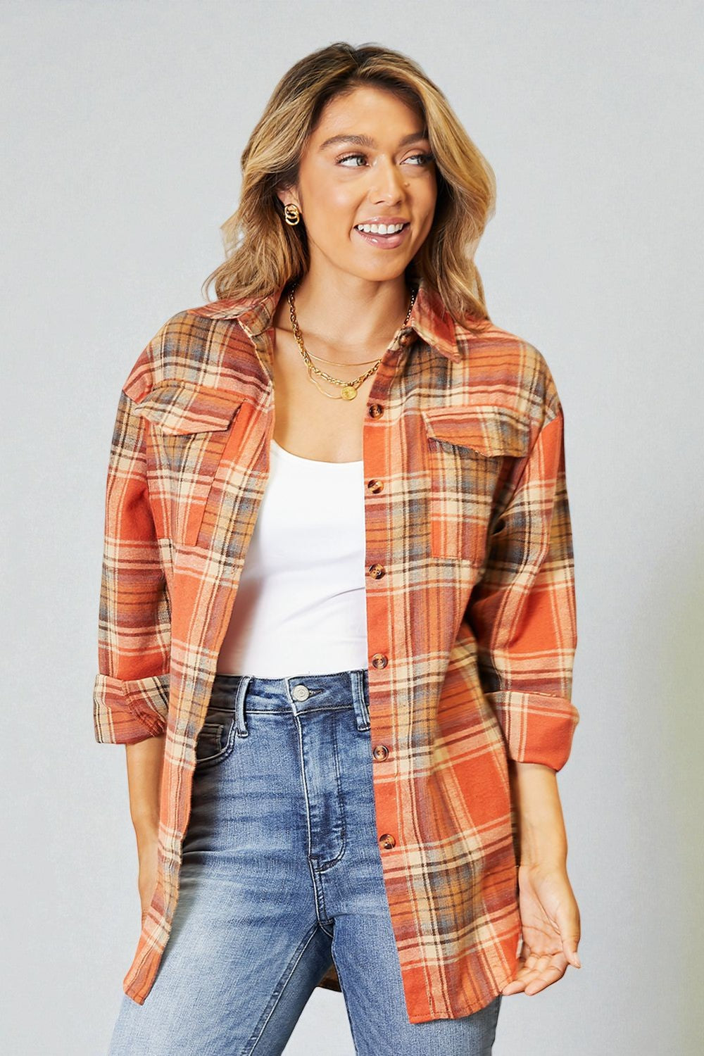 Woman wearing a plaid shirt and jeans against a plain background