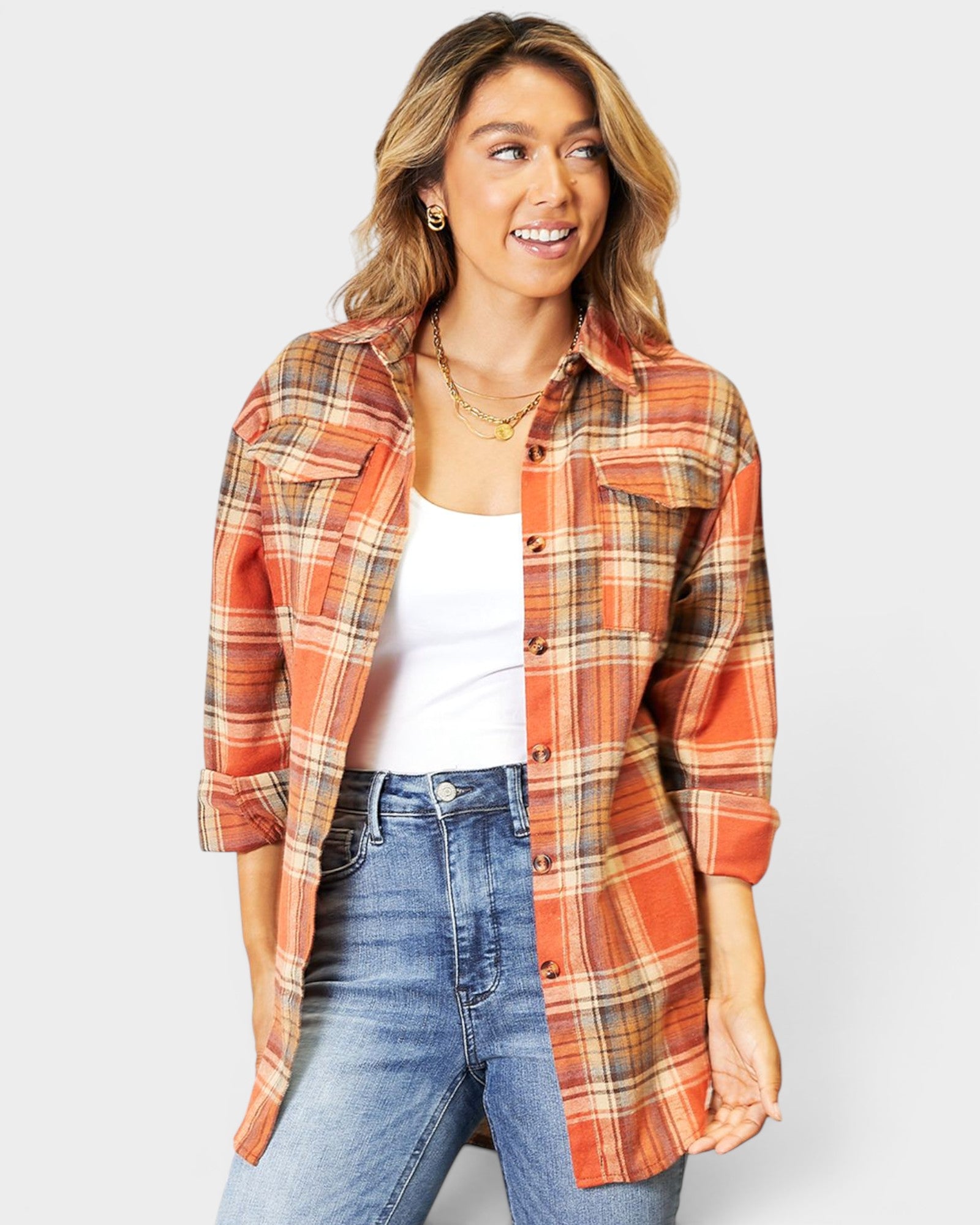 Woman wearing a plaid shirt over a white top and jeans on a light gray background