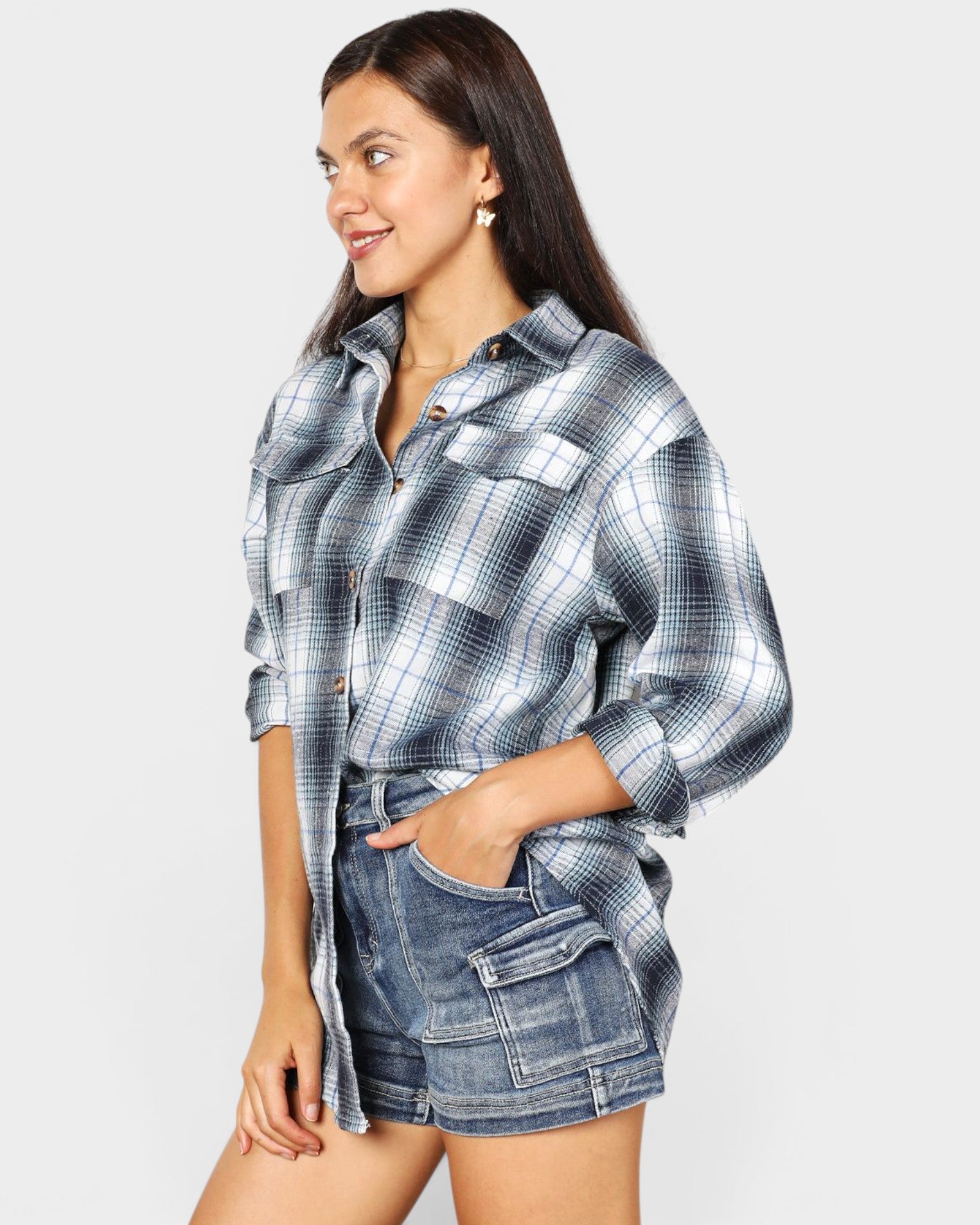 Woman wearing a plaid shirt and denim shorts on a light gray background
