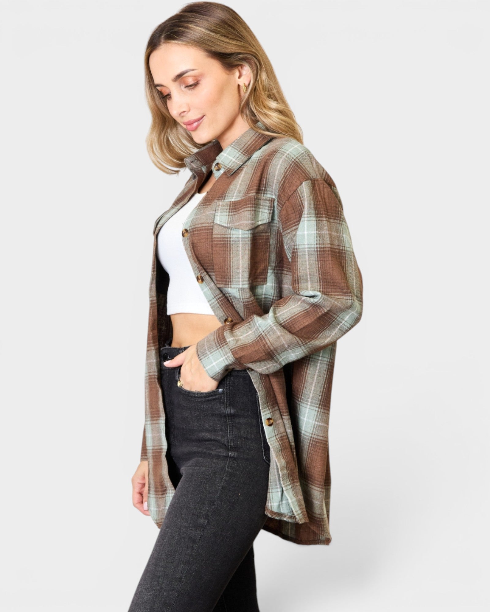Woman wearing a plaid shirt over a white top and black pants on a light gray background