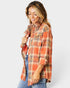 Woman wearing an orange plaid shirt with rolled-up sleeves on a white background