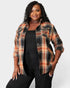 Woman wearing a plaid shirt over a black top and pants on a white background