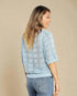 Woman wearing a light blue patterned sweater against a beige background