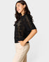 Woman wearing a black crochet top and beige pants on a white background
