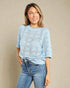 Woman wearing a light blue sweater and jeans against a beige background