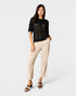 Woman wearing a black top and beige pants on a white background