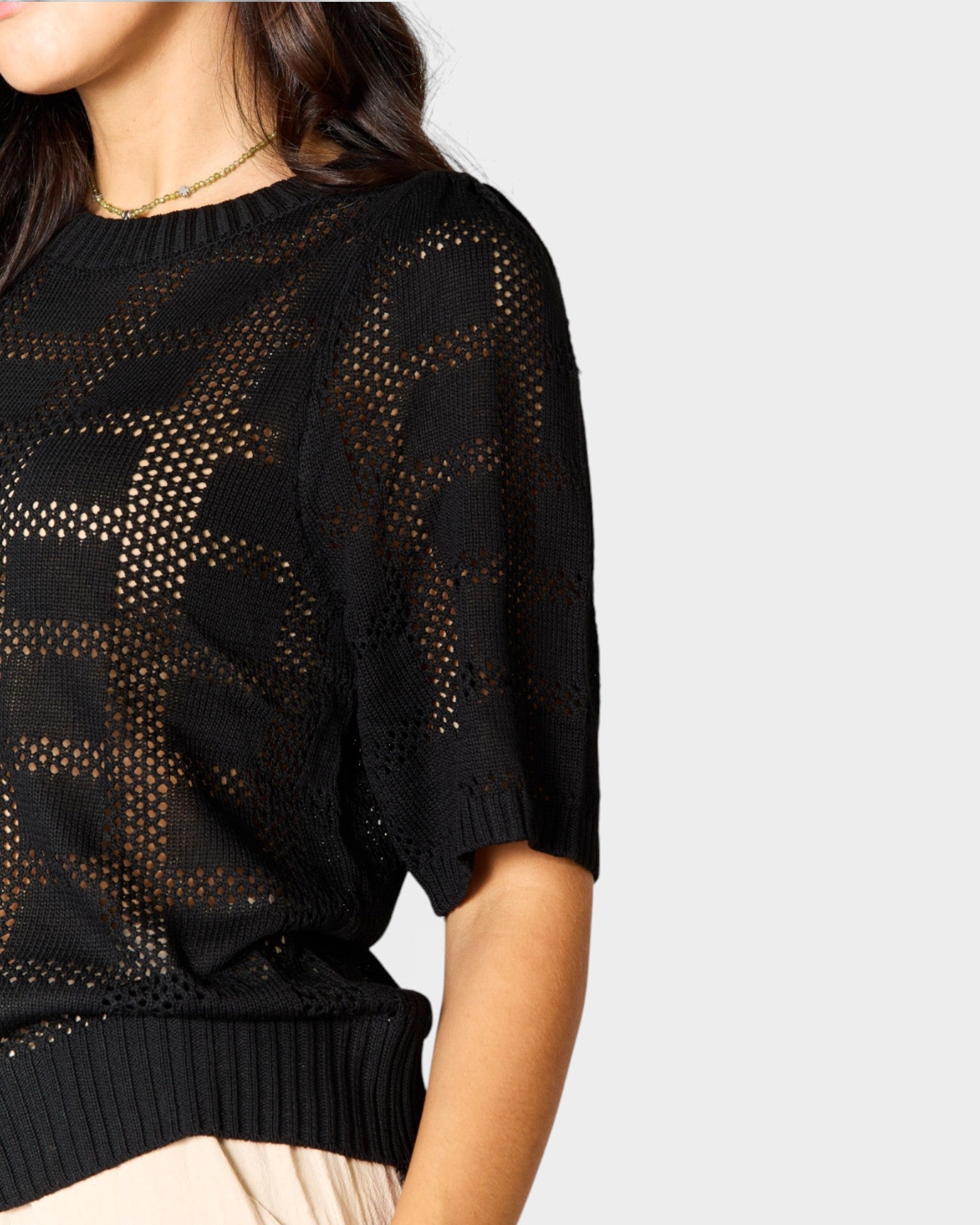 Black patterned sweater worn by a person on a light gray background