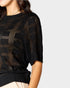 Black patterned sweater worn by a person on a light gray background