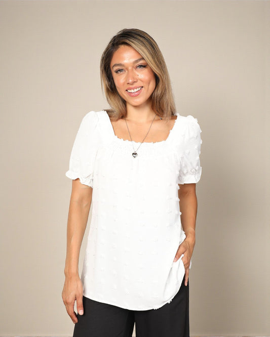 Woman wearing a white blouse with ruffled sleeves against a beige background
