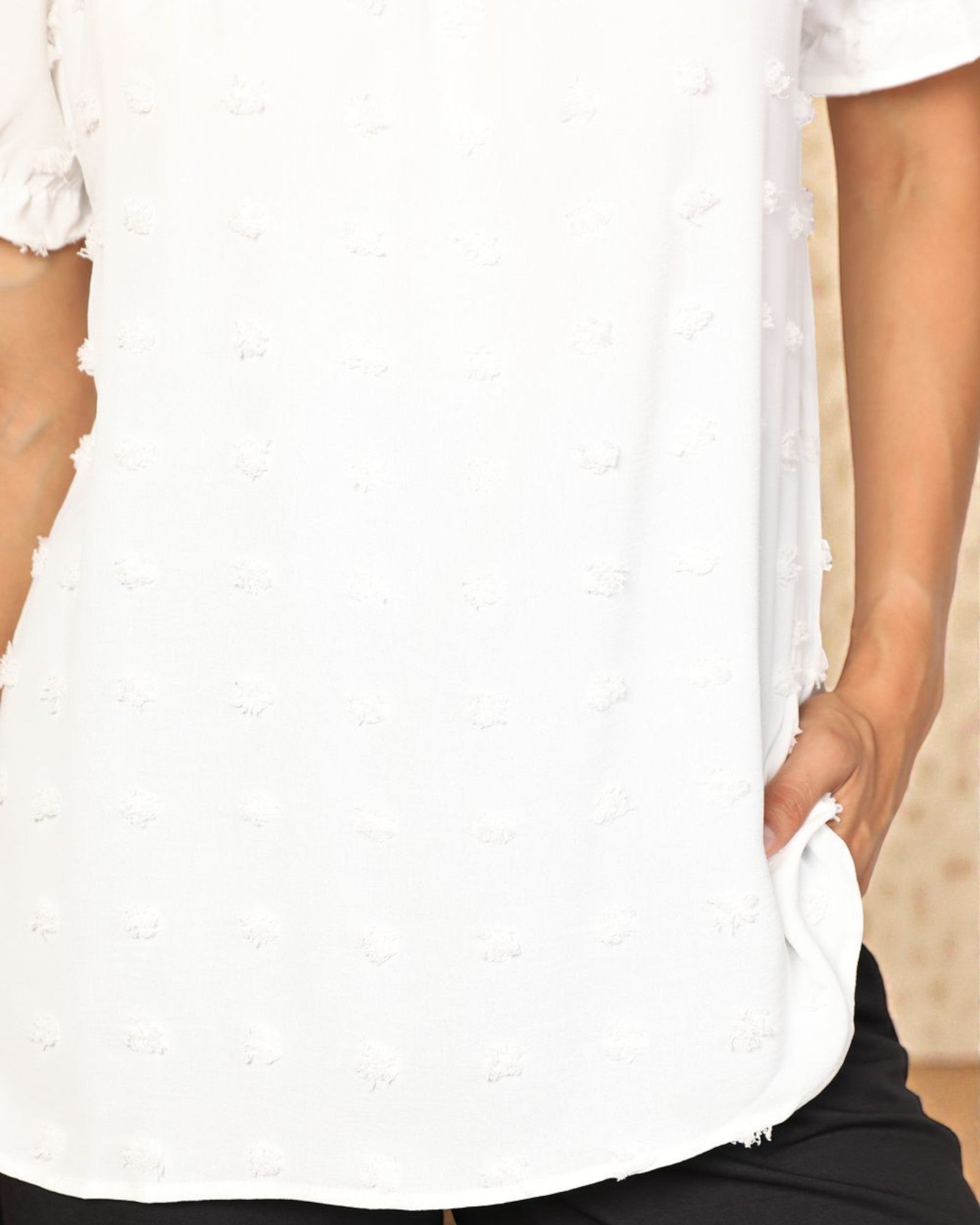 Close-up of a person wearing a white textured blouse with ruffled sleeves.