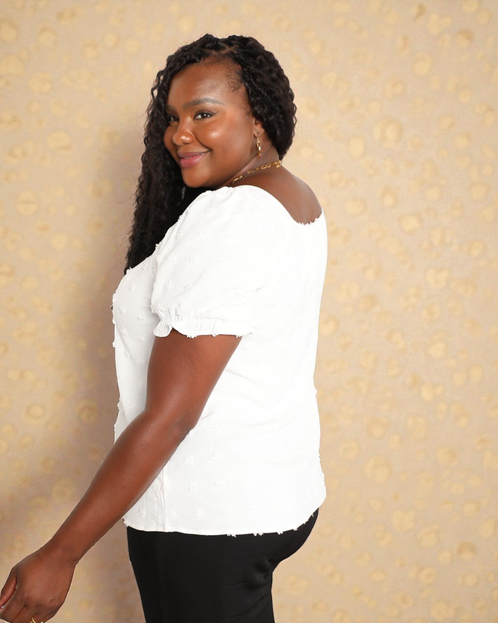Woman wearing a white blouse against a beige patterned background