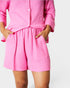 Person wearing a pink outfit with shorts and a top on a white background
