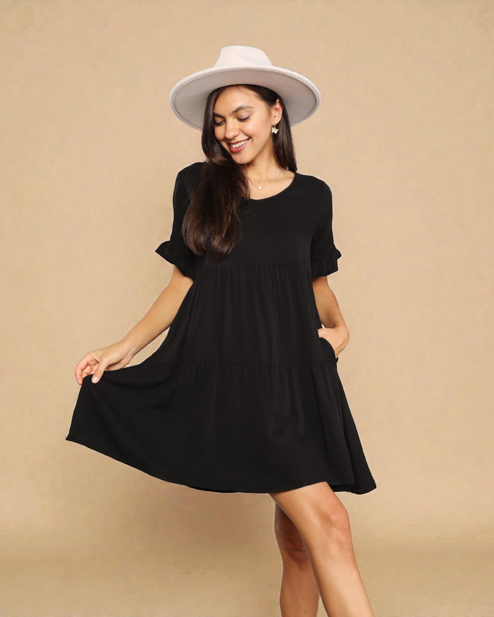 Woman wearing a black dress and white hat on a beige background