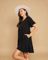 Woman wearing a black dress and white hat against a beige background