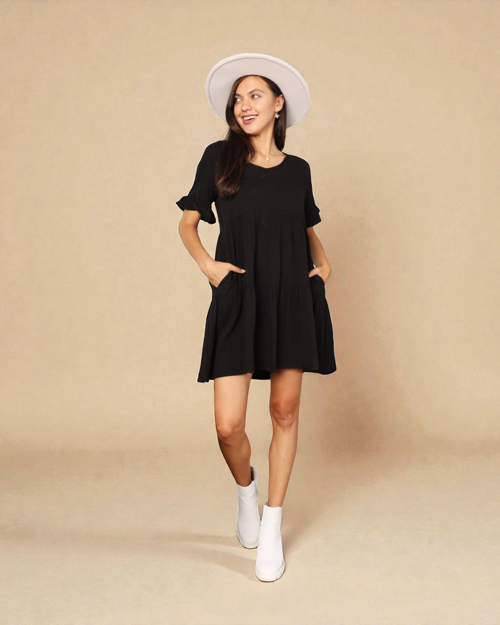 Woman wearing a black dress and white hat on a beige background