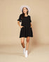 Woman wearing a black dress and white hat on a beige background