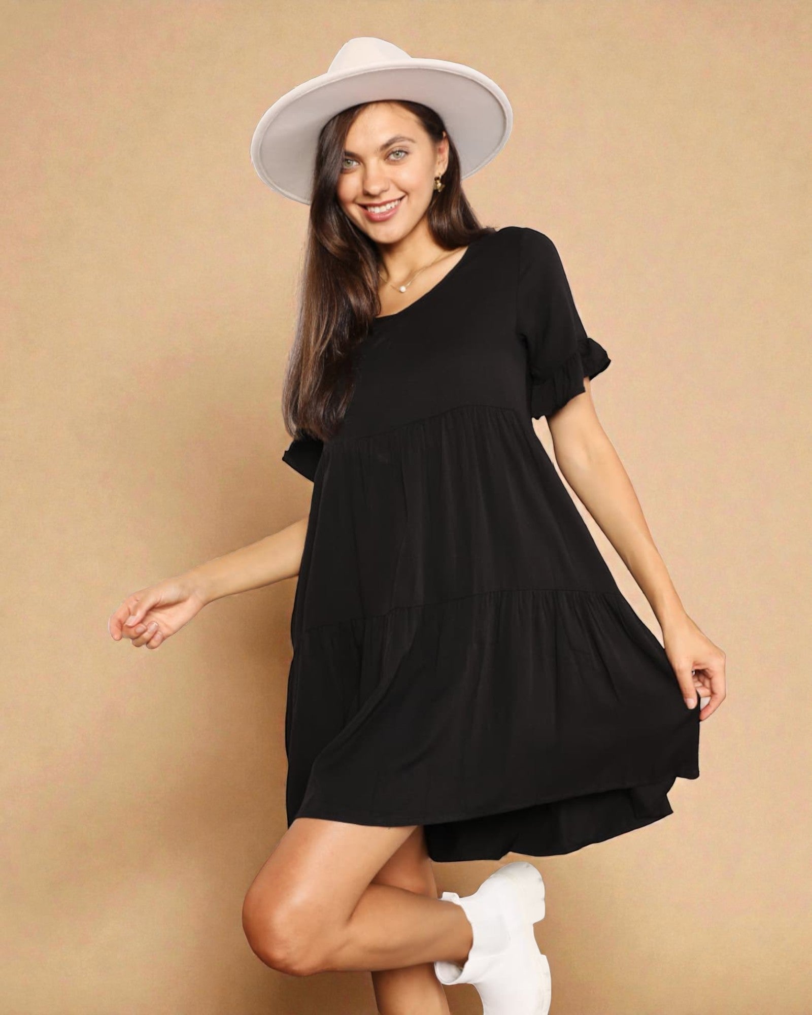 Woman wearing a black dress and white hat on a beige background